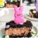 Slice of Easter dirt pudding cake on a white plate, topped with PEEPS.