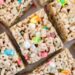 Lucky charms marshmallow treat bars cut into squares on parchment paper.